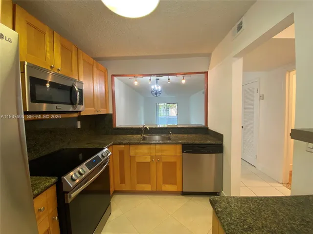 a kitchen with stainless steel appliances granite countertop a stove a sink and a microwave