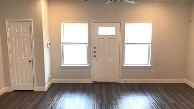 an empty room with wooden floor and windows