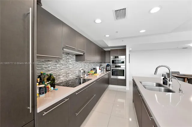 a large kitchen with stainless steel appliances a large counter top a stove and a refrigerator