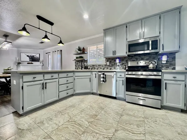 a kitchen with stainless steel appliances granite countertop a stove a sink and a microwave