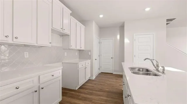 a kitchen with a sink dishwasher a stove and white cabinets with wooden floor