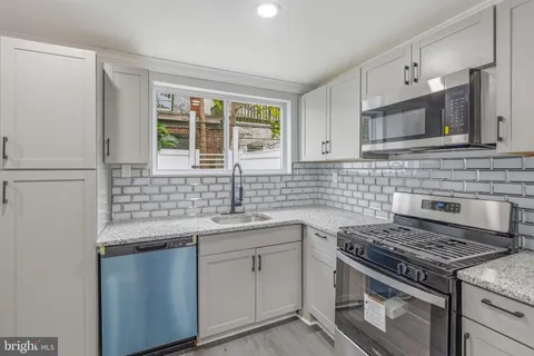 an empty room with wooden floor staircase and windows