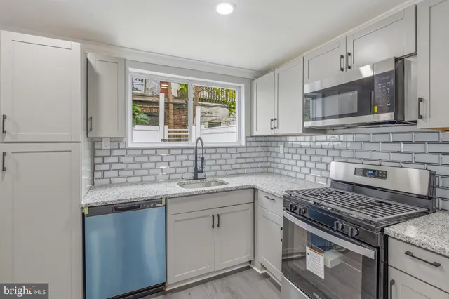 an empty room with wooden floor staircase and windows