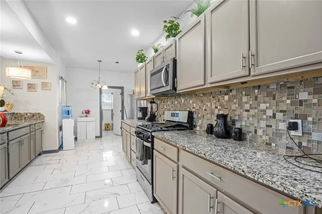 a kitchen with stainless steel appliances granite countertop a sink stove and cabinets
