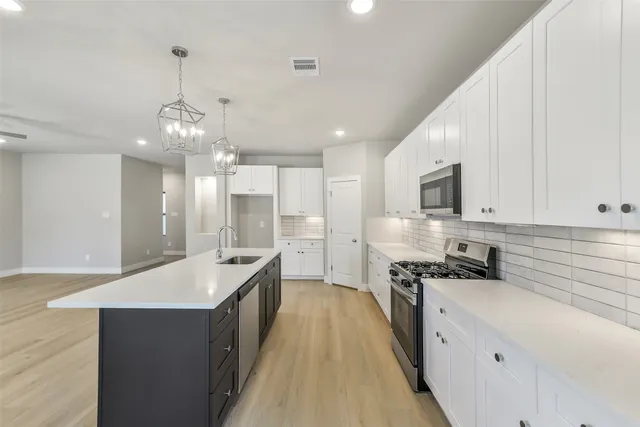 a kitchen with granite countertop white cabinets and stainless steel appliances