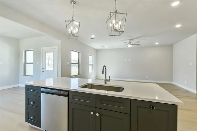 a kitchen with granite countertop stainless steel appliances a sink stove and wooden floor