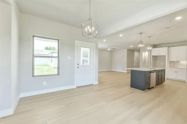 a view of a kitchen with granite countertop a stove top oven a sink dishwasher with wooden floor and cabinets