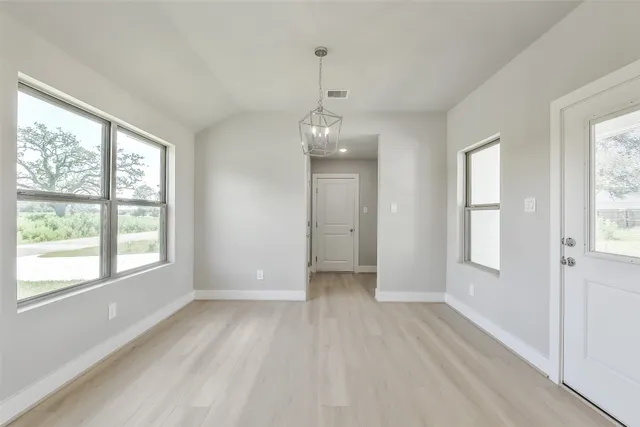 a view of an empty room with kitchen and window