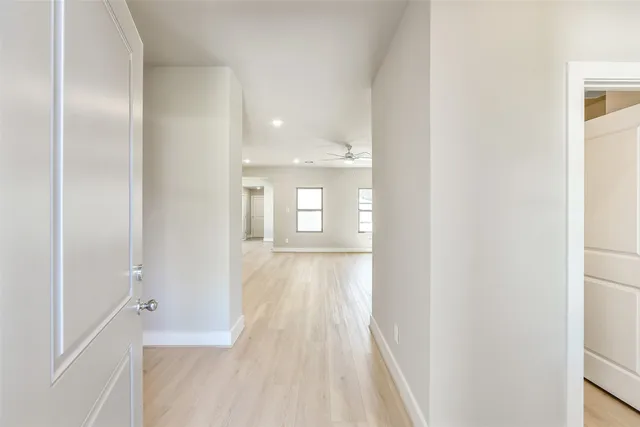 a view of a hallway with wooden floor and a bathroom