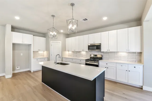 a view of kitchen with kitchen island stainless steel appliances refrigerator sink and cabinets