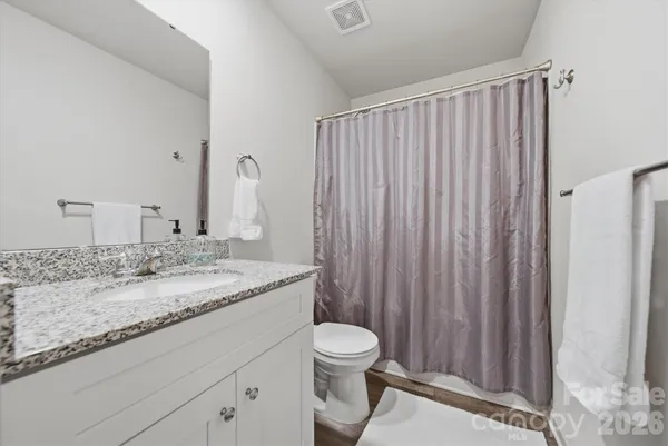 a bathroom with a granite countertop sink toilet and a mirror