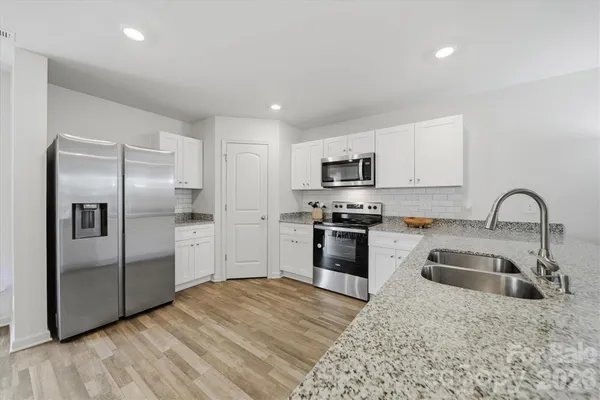 a kitchen with granite countertop a refrigerator and a sink