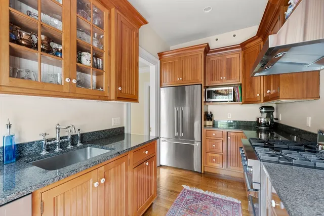 a kitchen with stainless steel appliances granite countertop a refrigerator a stove and a sink with wooden cabinets
