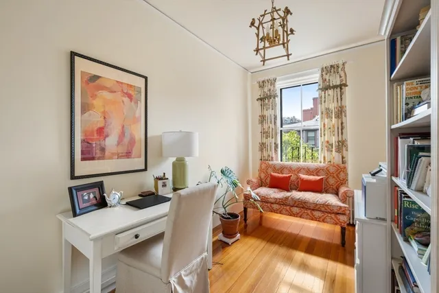 a living room with furniture a bookshelf and a window