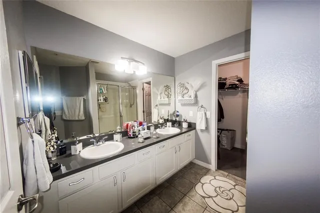 a bathroom with a granite countertop shower sink vanity and mirror