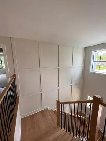 a view of hallway with window and wooden floor