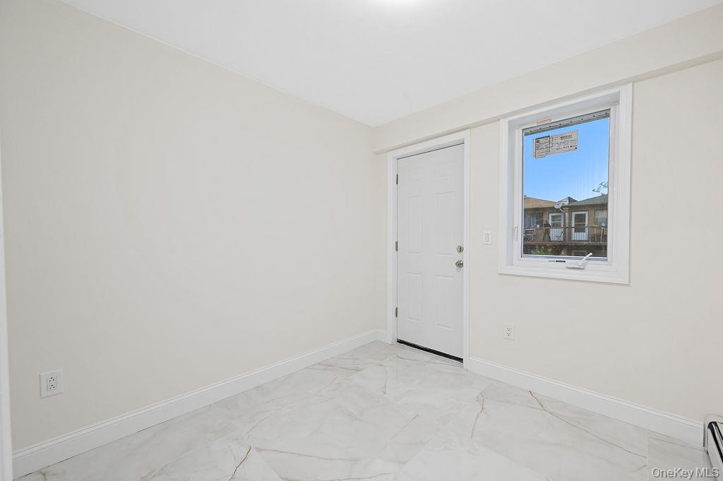 10603 49th Avenue Queens, NY 11368 - Photo 16 of 32 Empty room with light marble finish floors, baseboards, and baseboard heating