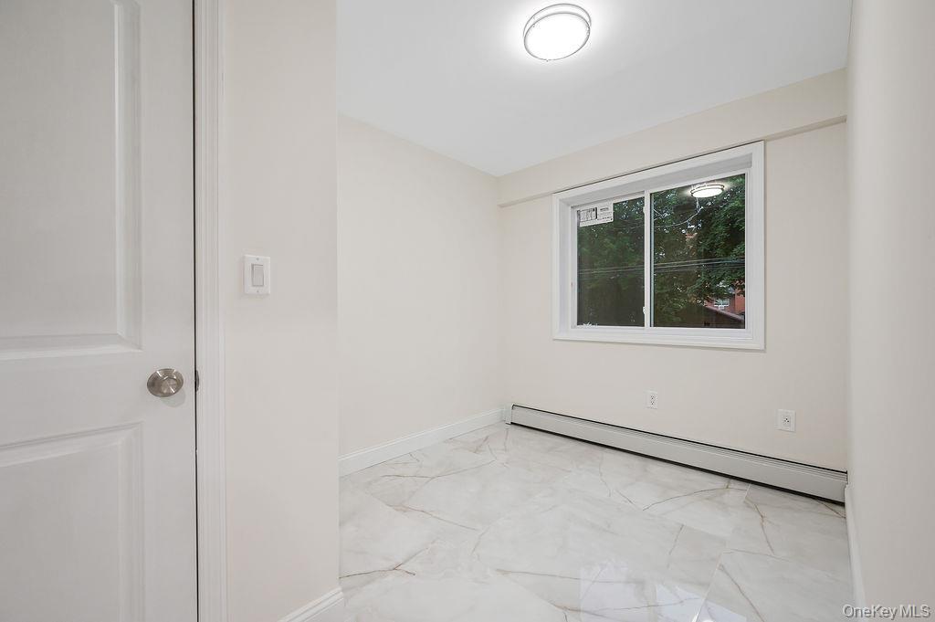 10603 49th Avenue Queens, NY 11368 - Photo 17 of 32 Unfurnished room featuring baseboard heating, light marble finish floors, and baseboards