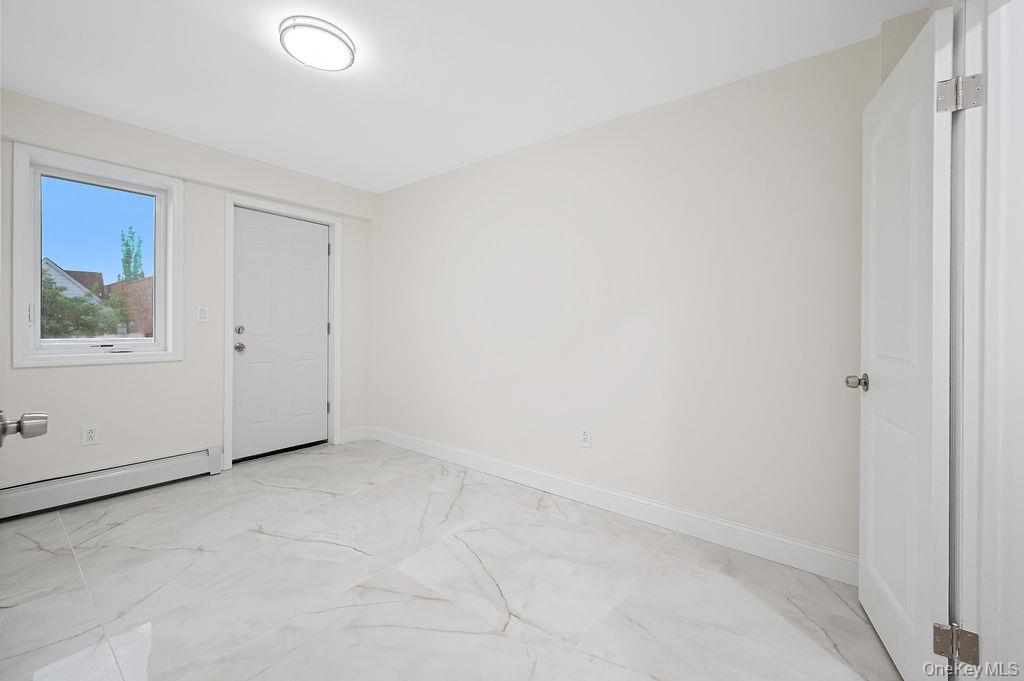 10603 49th Avenue Queens, NY 11368 - Photo 6 of 32 Bedroom with half bath, baseboard radiator, light marble finish floors, and baseboards
