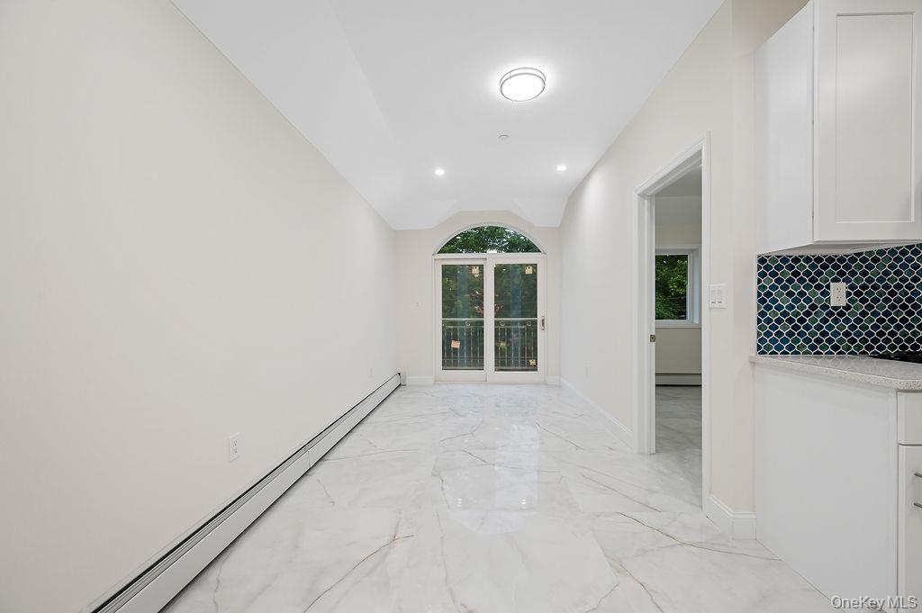 10603 49th Avenue Queens, NY 11368 - Photo 8 of 32 Hall with a baseboard radiator, light marble finish floors, vaulted ceiling, and baseboards