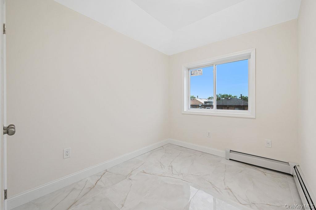 10603 49th Avenue Queens, NY 11368 - Photo 9 of 32 Empty room with light marble finish floors, baseboards, and a baseboard heating unit