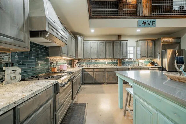 a kitchen with stainless steel appliances granite countertop a kitchen island a stove a sink a dining table and chairs