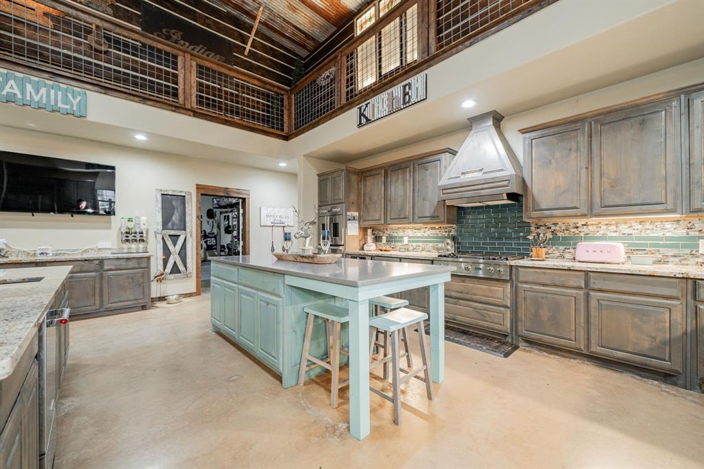 1990 Jim Harry Loop Sunset, TX 76270 - Photo 17 of 40 a kitchen with stainless steel appliances granite countertop a kitchen island a stove a sink a dining table and chairs