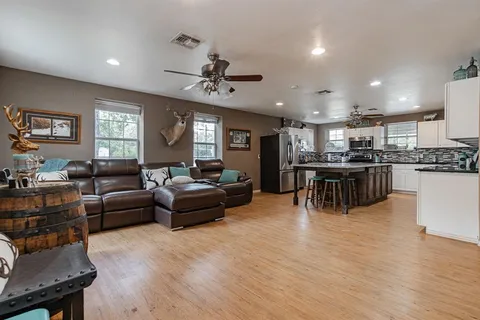 a living room with stainless steel appliances kitchen island furniture and a flat screen tv