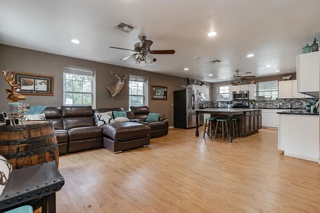 a living room with stainless steel appliances kitchen island furniture and a flat screen tv