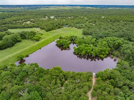a view of a lake with a yard and large trees