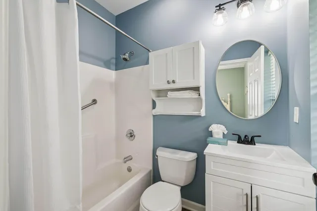 a bathroom with a toilet sink vanity tub and mirror