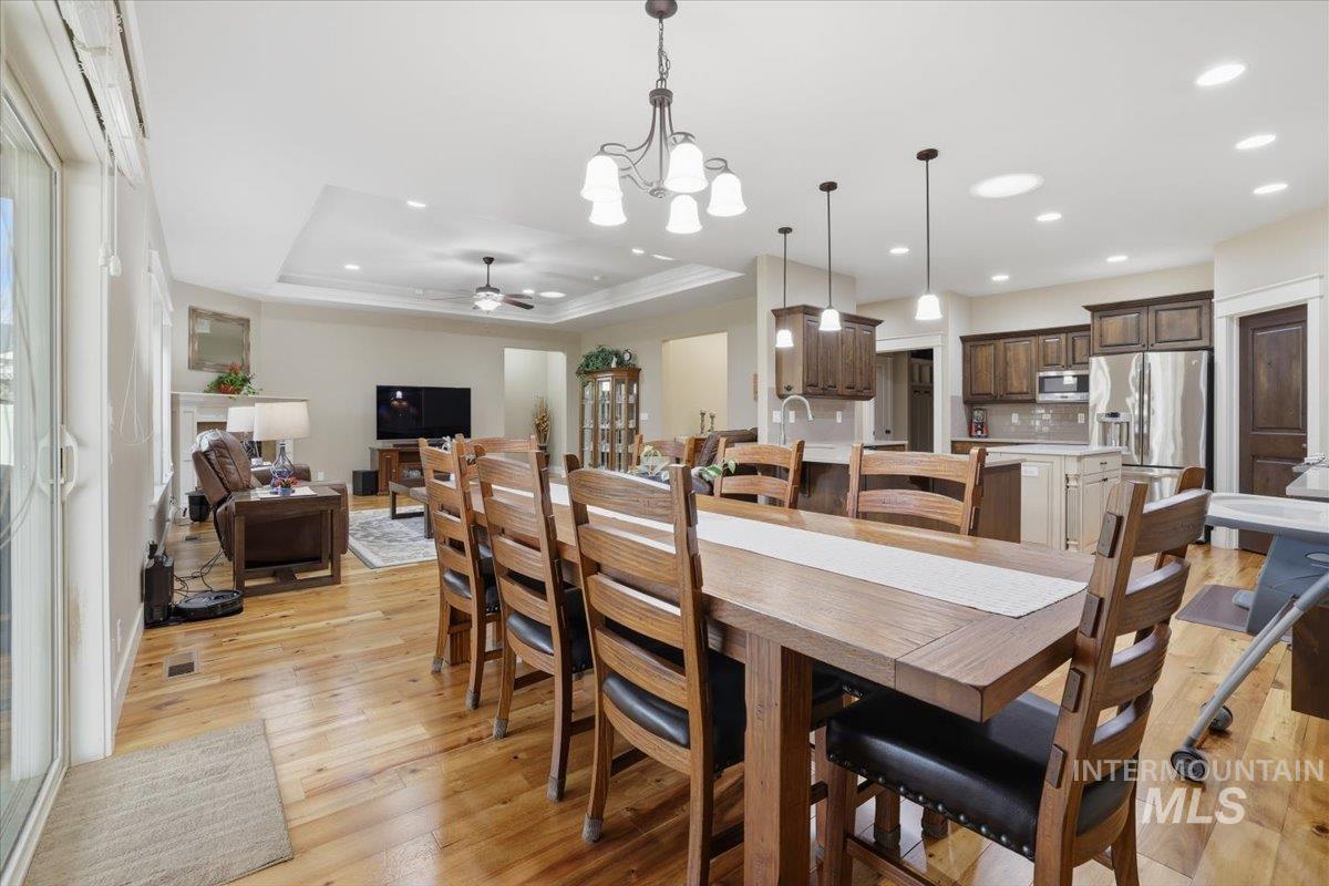 4604 Middlesboro Way Caldwell, ID 83607 - Photo 12 of 43 Dining space with a chandelier, light wood-type flooring, a ceiling fan, a raised ceiling, and recessed lighting