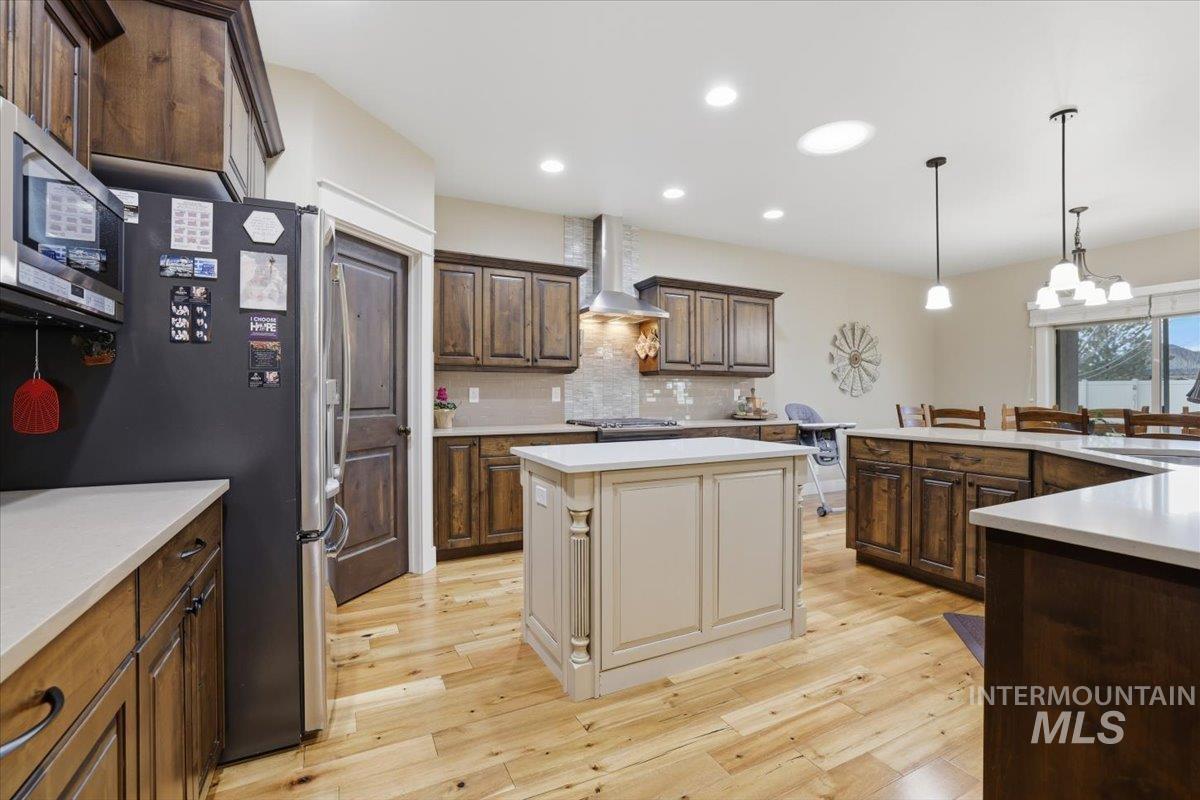 4604 Middlesboro Way Caldwell, ID 83607 - Photo 15 of 43 Kitchen featuring dark brown cabinetry, decorative light fixtures, stainless steel appliances, a kitchen island, and light wood-type flooring