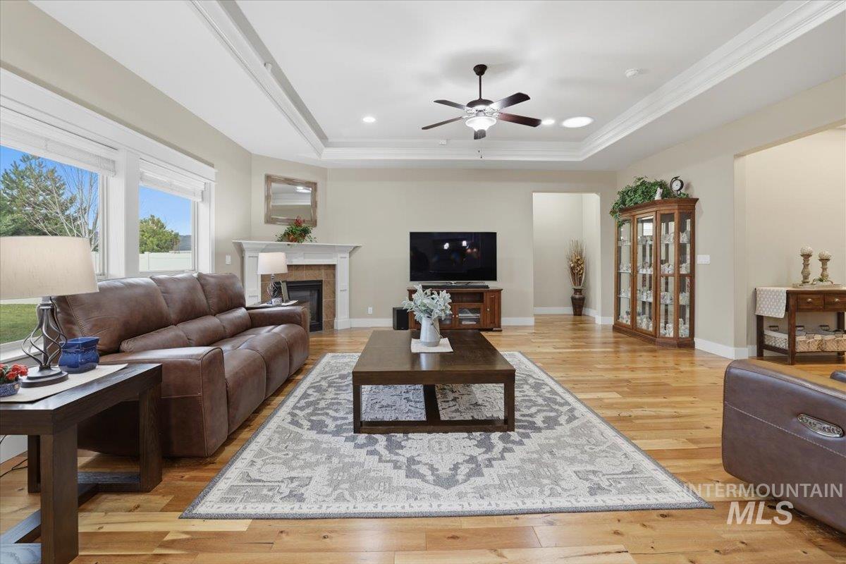 4604 Middlesboro Way Caldwell, ID 83607 - Photo 7 of 43 Living room with light wood-style floors, a fireplace, a ceiling fan, a tray ceiling, and crown molding