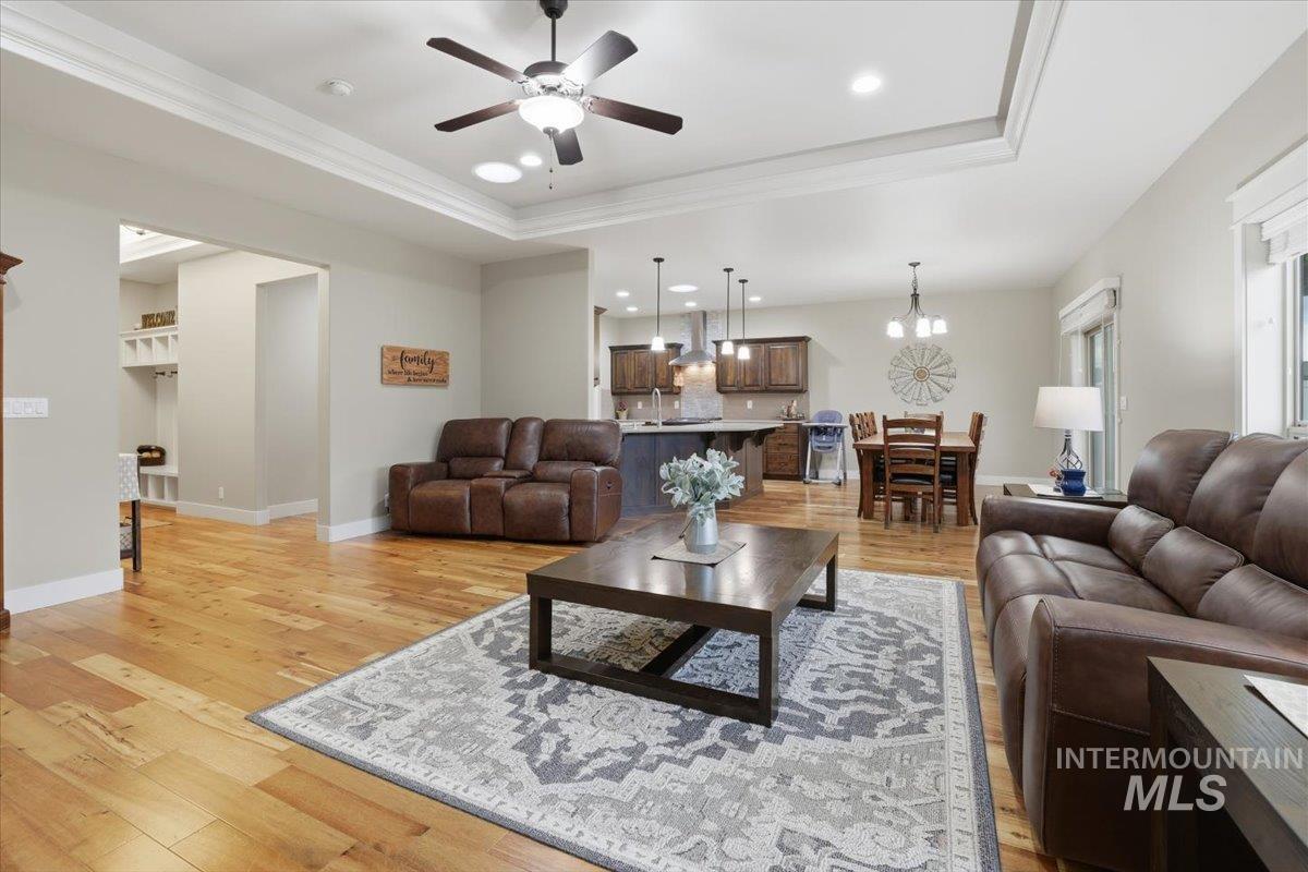 4604 Middlesboro Way Caldwell, ID 83607 - Photo 9 of 43 Living area featuring light wood-type flooring, ornamental molding, a ceiling fan, a chandelier, and a tray ceiling