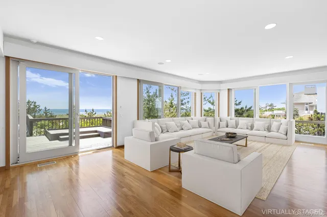a living room with furniture large windows and wooden floor
