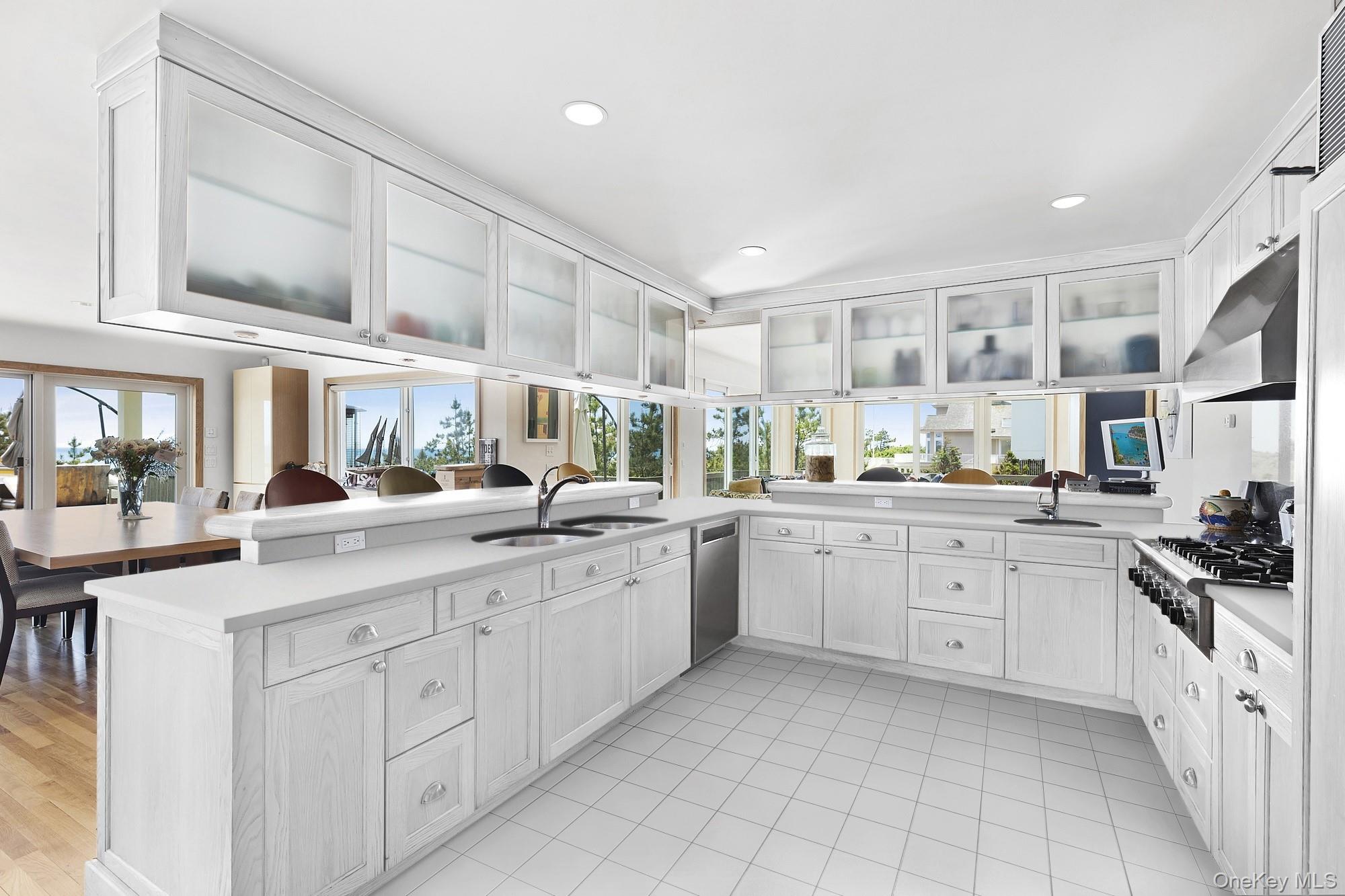 63-65 Dune Road Quogue, NY 11959 - Photo 6 of 29 a kitchen with white cabinets and white appliances