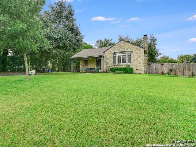 a view of a house with a big yard potted plants and large tree