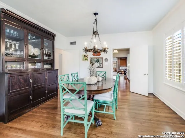 a dining room with wooden floor a chandelier a wooden table and chairs