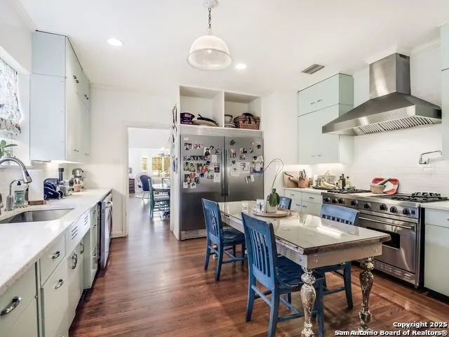 a kitchen with stainless steel appliances a dining table chairs stove and cabinets