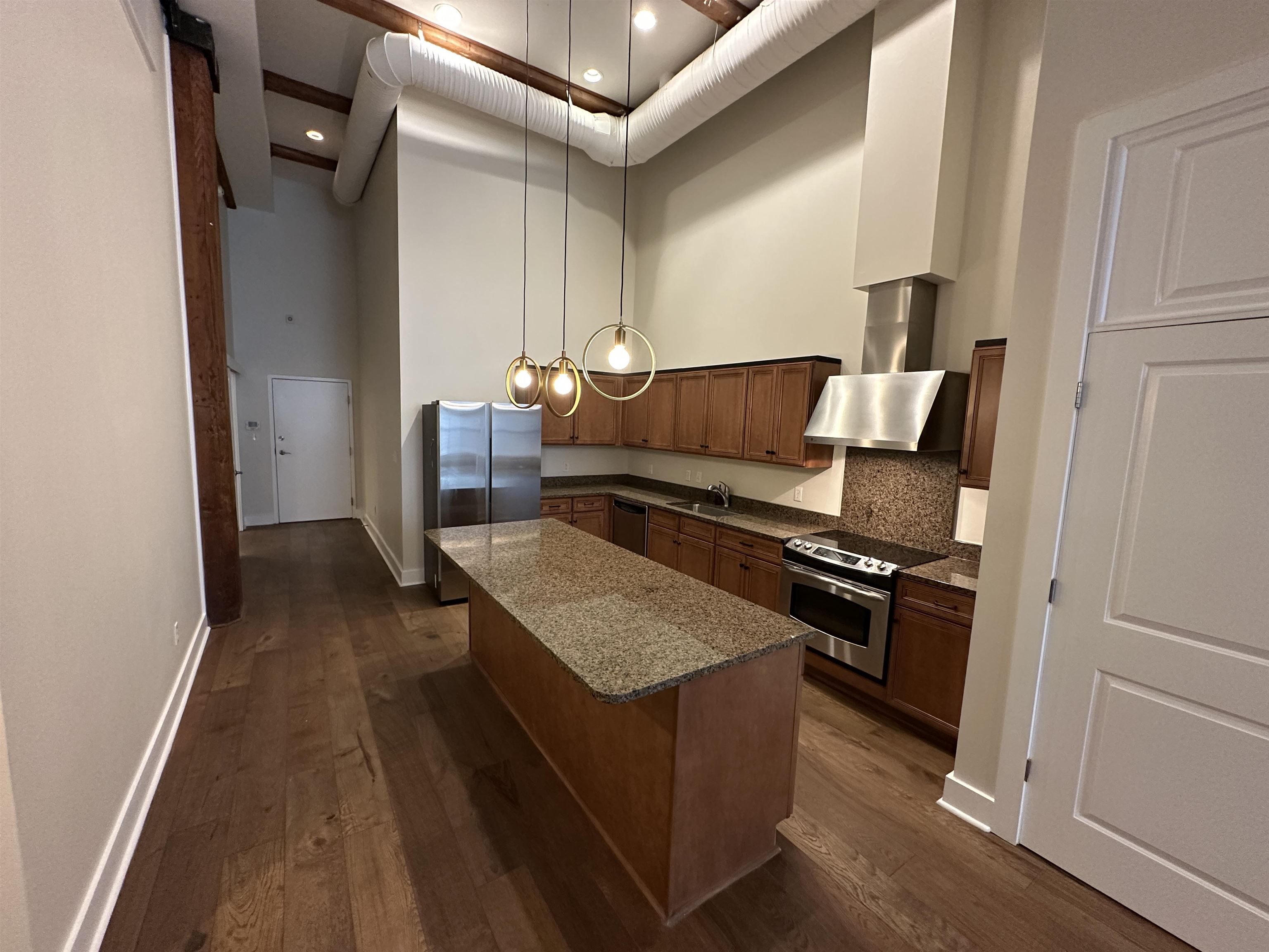 435 South Front Street, Unit 109 Memphis, TN 38103 - Photo 16 of 25 Kitchen featuring dark wood-style flooring, a center island, a high ceiling, tasteful backsplash, and dark stone counters