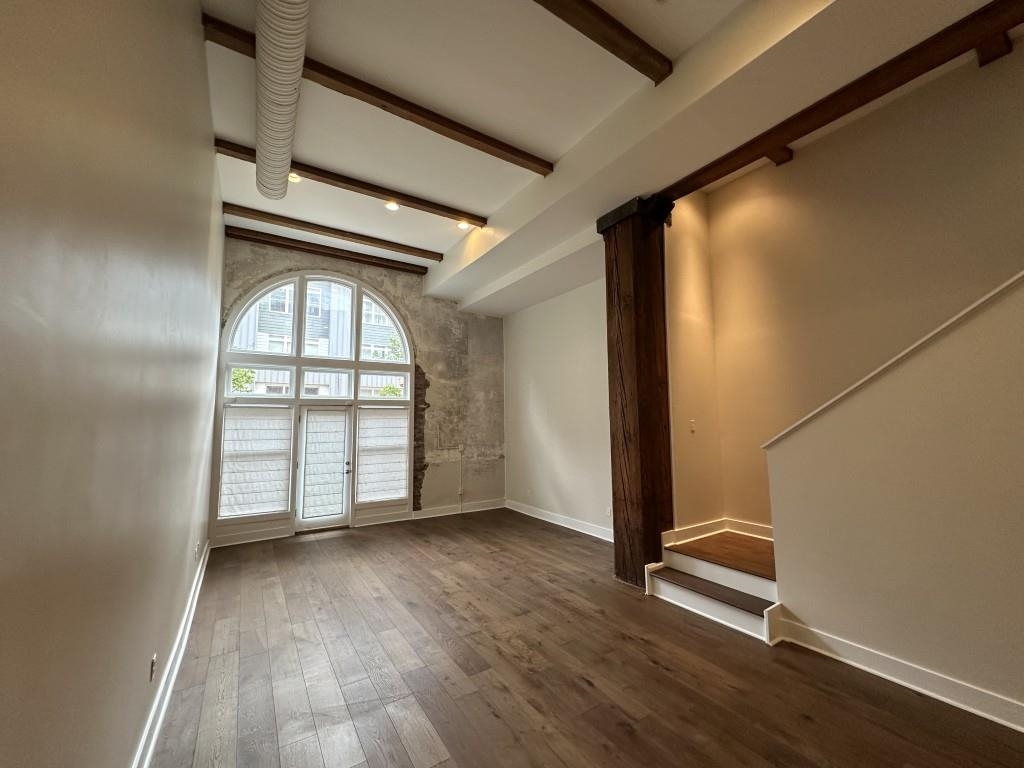 435 South Front Street, Unit 109 Memphis, TN 38103 - Photo 2 of 25 Unfurnished living room featuring beam ceiling and dark wood-style floors