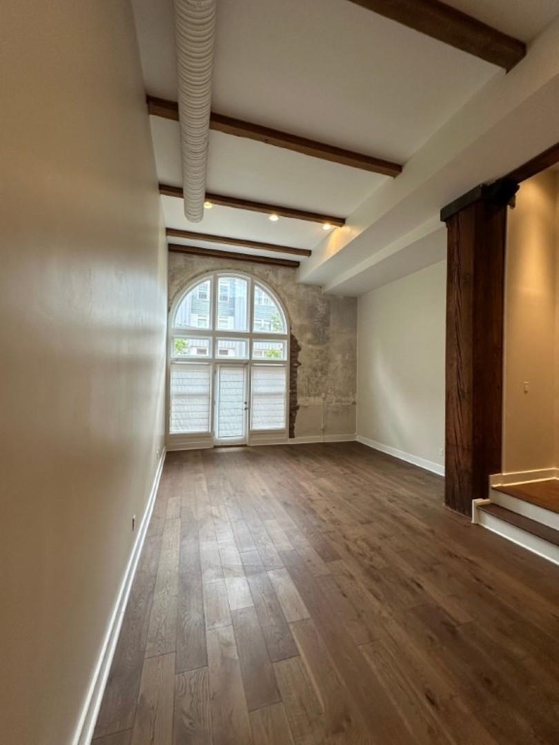 435 South Front Street, Unit 109 Memphis, TN 38103 - Photo 3 of 25 Unfurnished room featuring dark wood-style flooring and beam ceiling