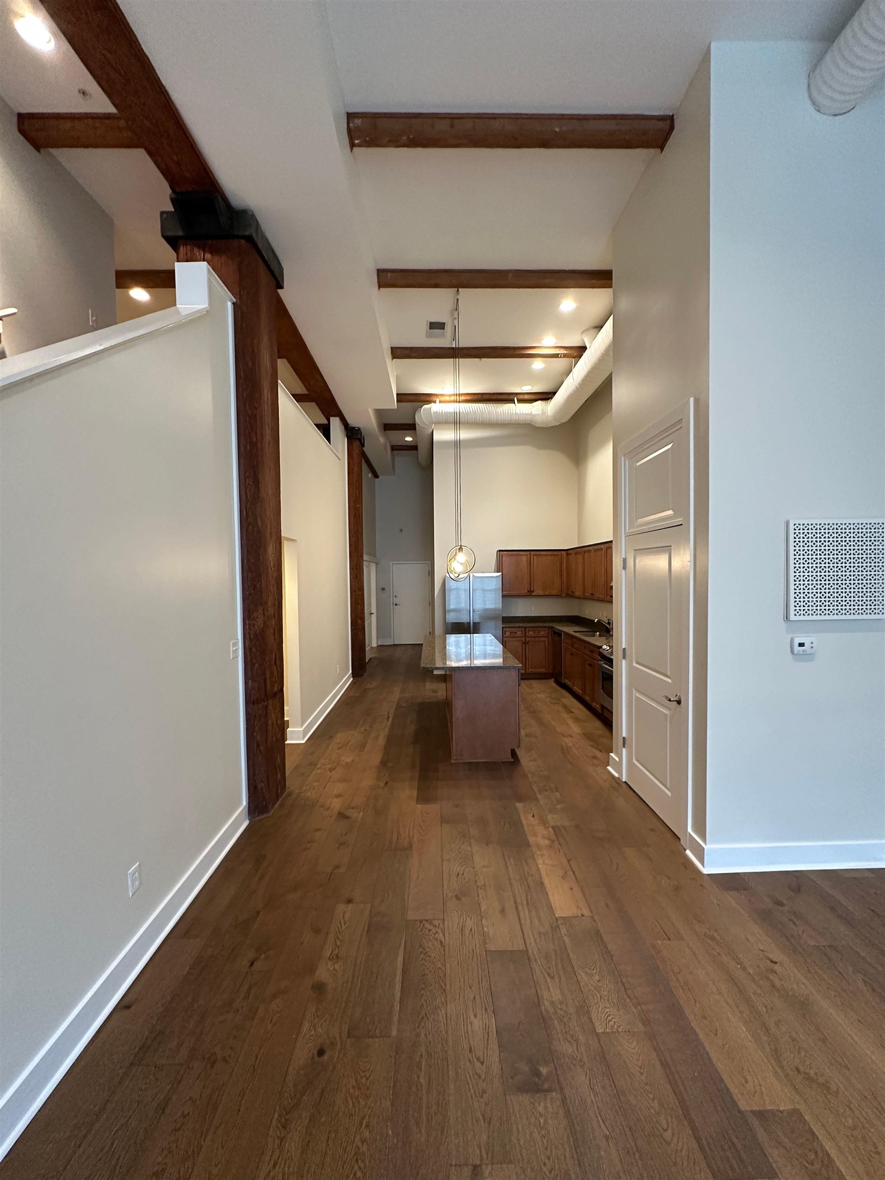 435 South Front Street, Unit 109 Memphis, TN 38103 - Photo 25 of 25 Kitchen featuring a center island, open floor plan, dark wood-style flooring, decorative light fixtures, and wood finish cabinets