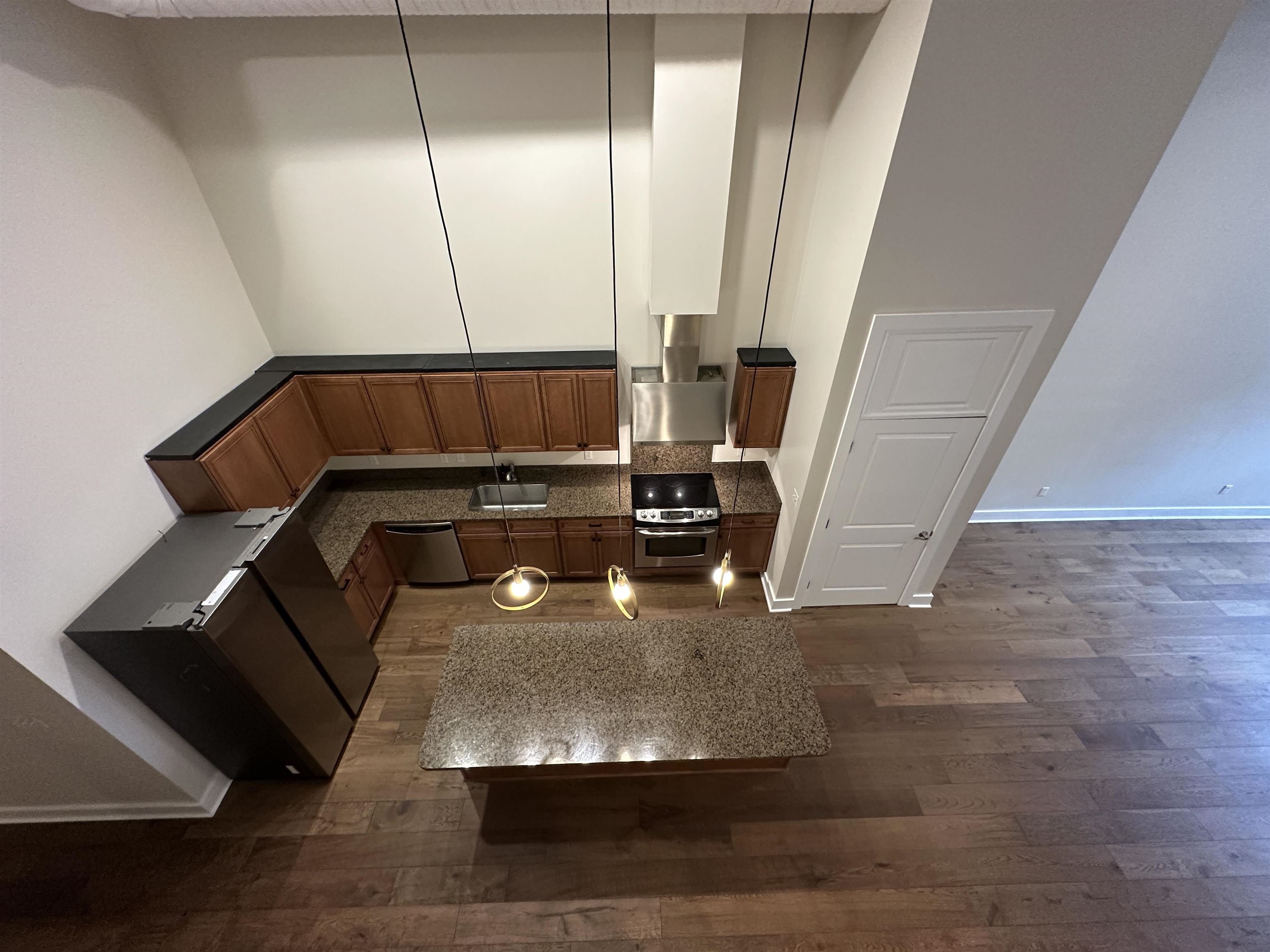 435 South Front Street, Unit 109 Memphis, TN 38103 - Photo 6 of 25 Kitchen with dark wood-style floors, stainless steel appliances, a high ceiling, wood finish cabinetry, and dark stone counters