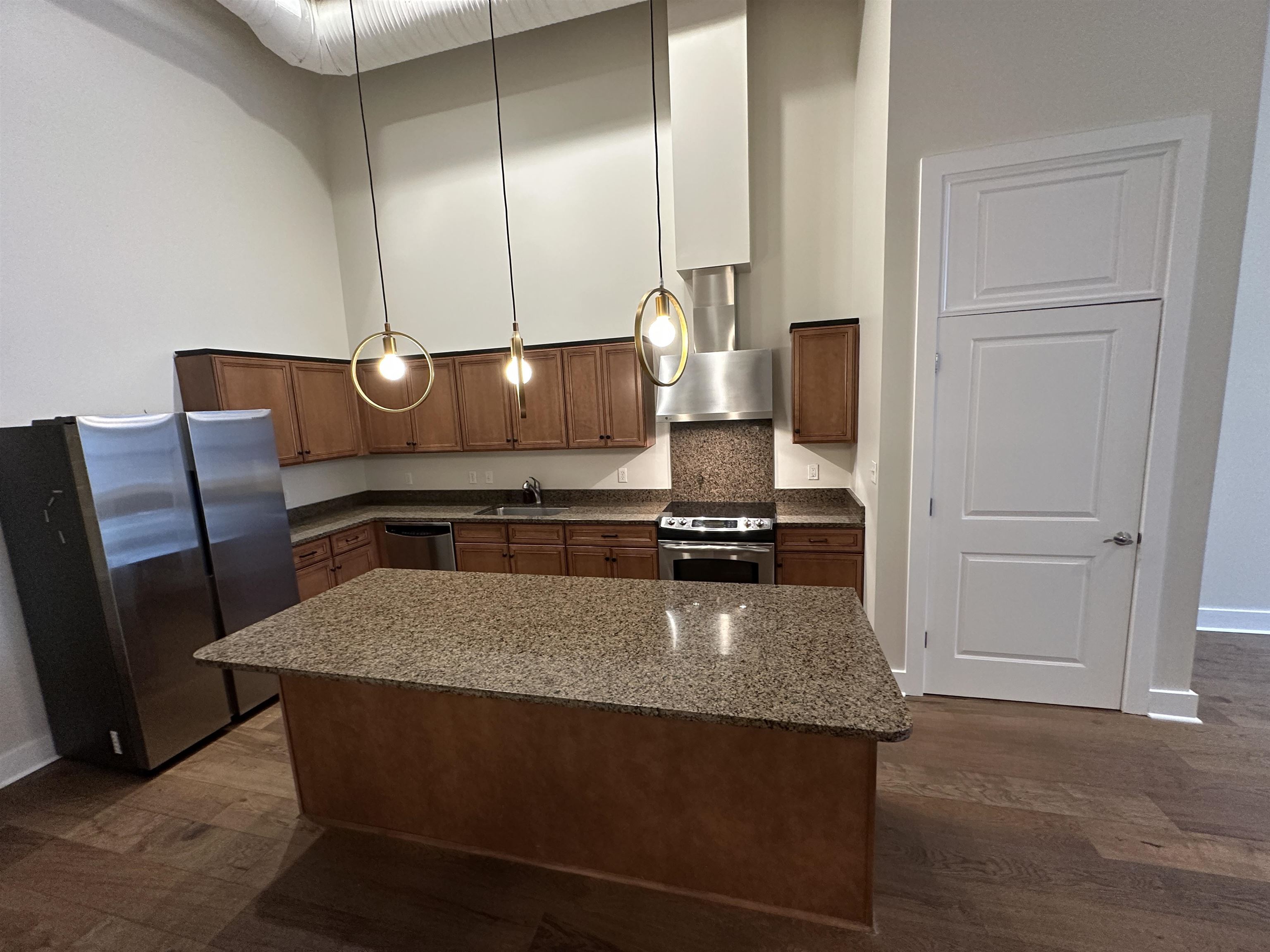 435 South Front Street, Unit 109 Memphis, TN 38103 - Photo 7 of 25 Kitchen featuring stainless steel appliances, a high ceiling, dark wood-style floors, a center island, and dark stone counters