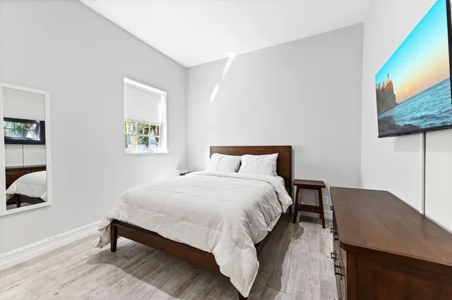 a bedroom with a bed lamps and wooden floor