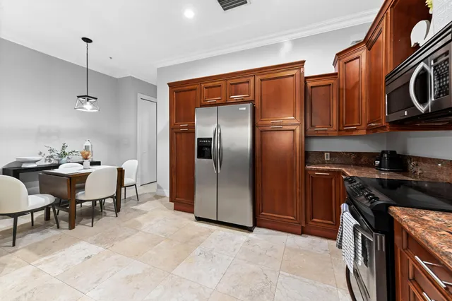 a kitchen with stainless steel appliances granite countertop a refrigerator a stove a sink and a dining table