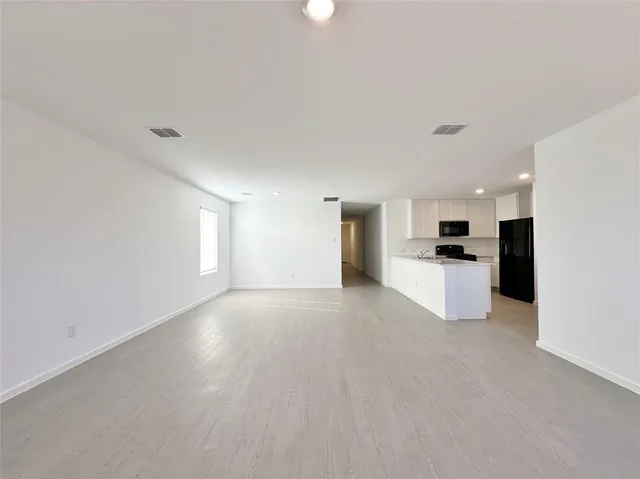 a view of a kitchen with a sink and dishwasher a refrigerator with white cabinets