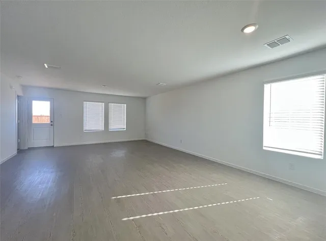 an empty room with a window and wooden floor